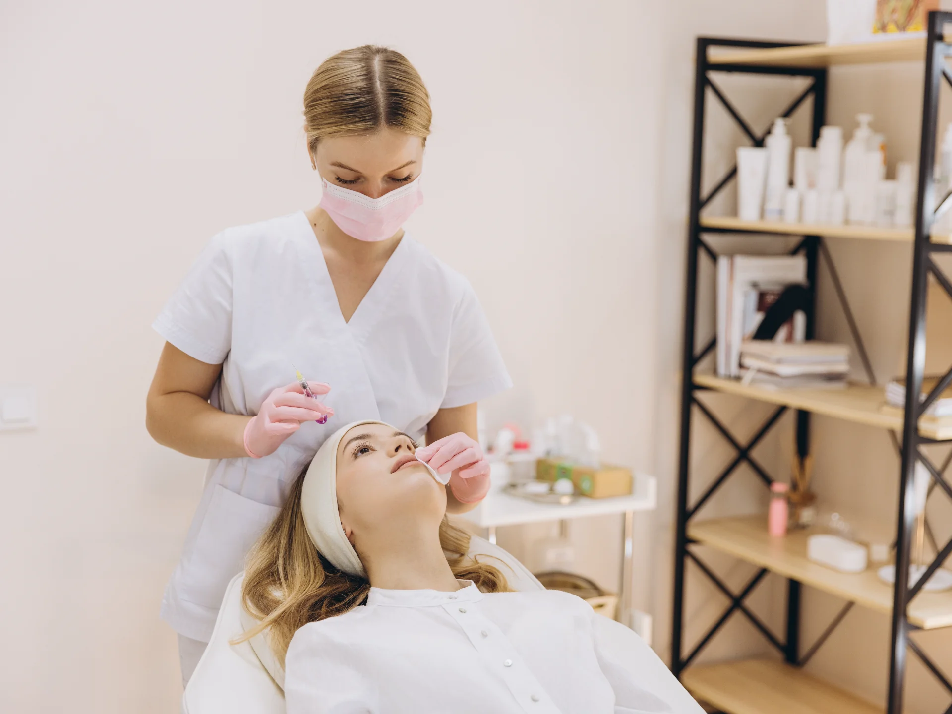 beautician performing botox injection on forehead of young woman